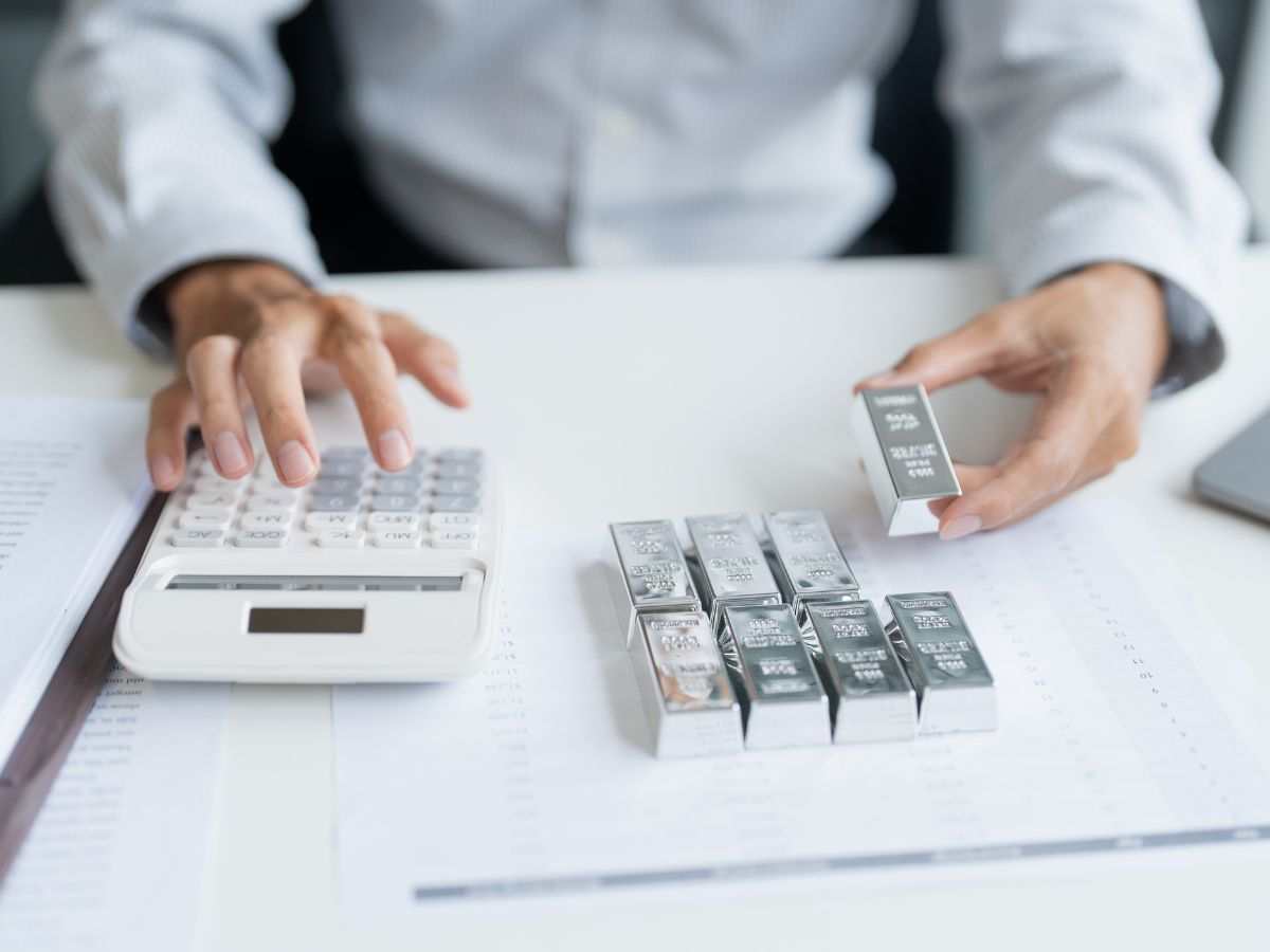 persona con lingotti d'argento e calcolatrice