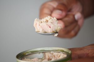 uomo che tiene in mano cucchiaio con tonno